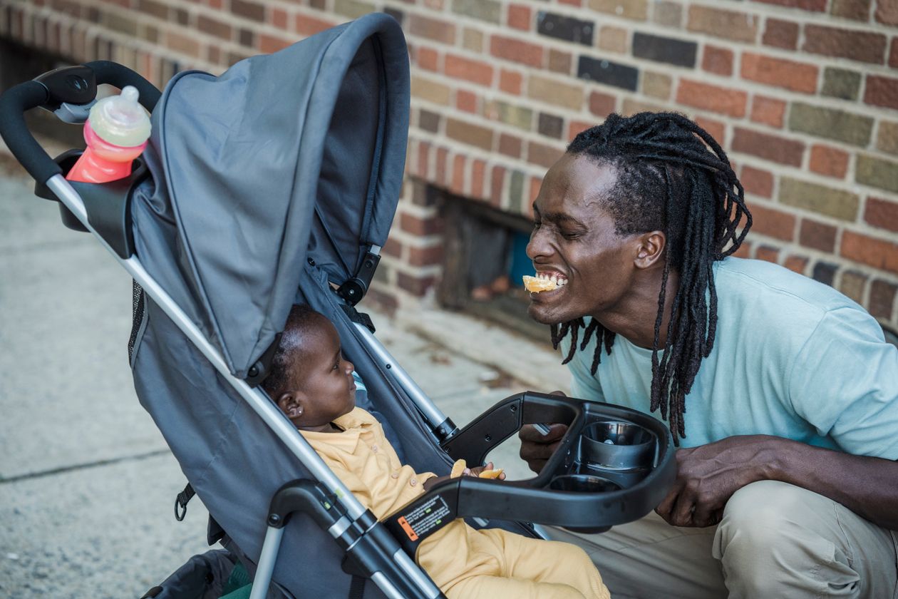 Father playing with his baby sitting in a stroller