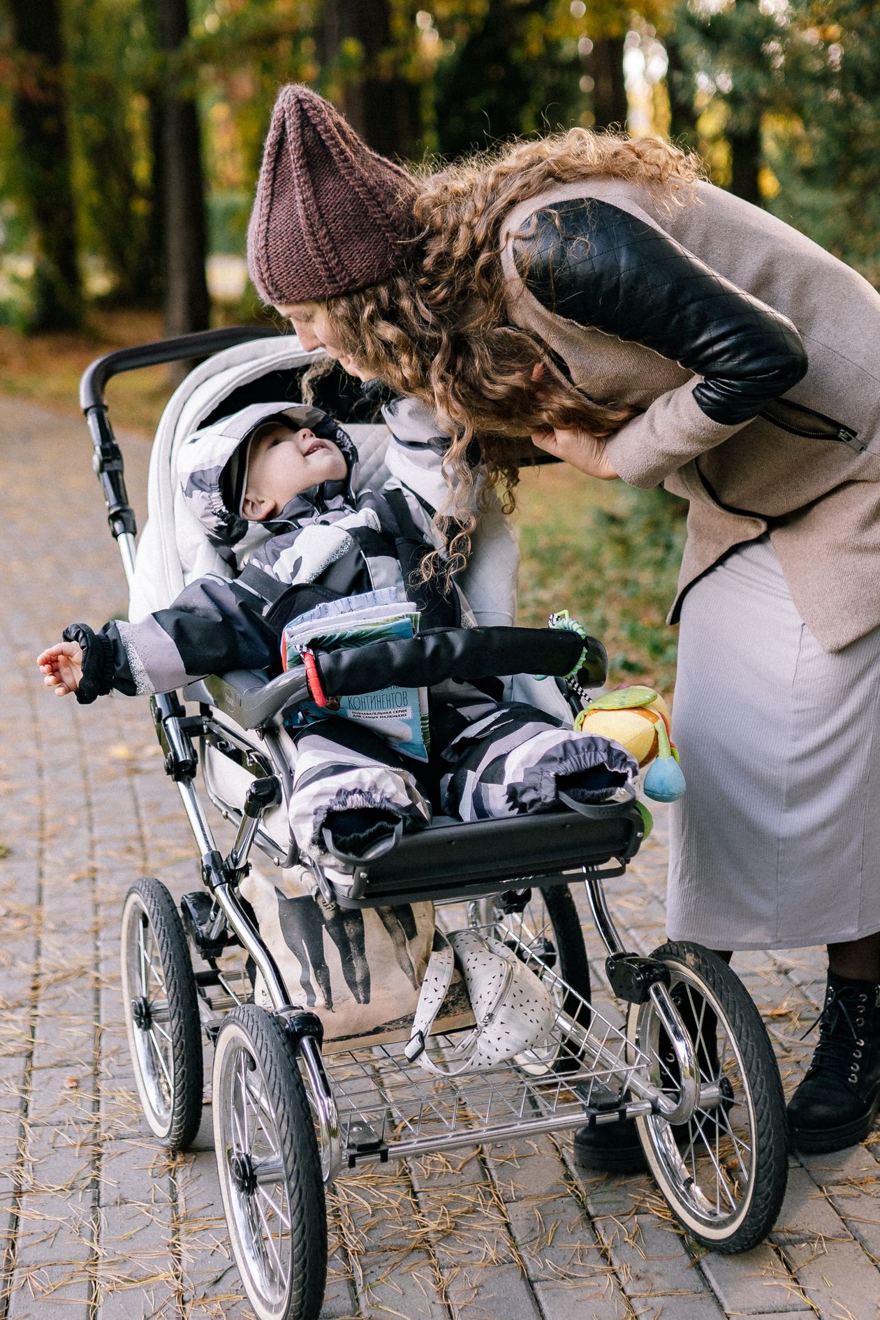 Parent checking on a baby in a stroller at the park